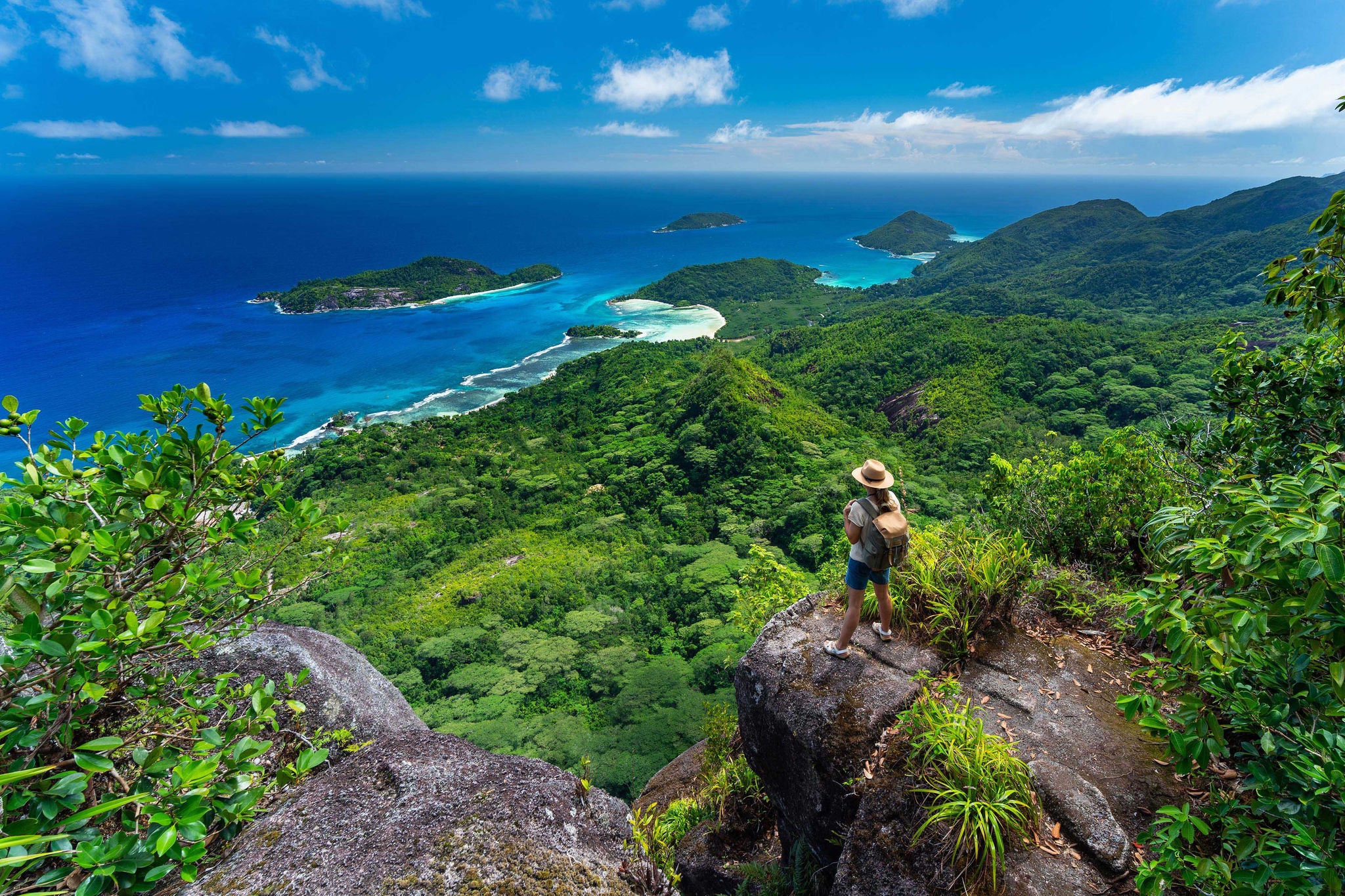 Female hiker standing high above Indian ocean on tropical island enjoying amazing view